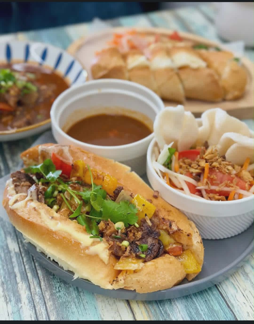 Vietnamese bánh mì on a French baguette with lemongrass beef, pickled vegetables, and dipping broth.