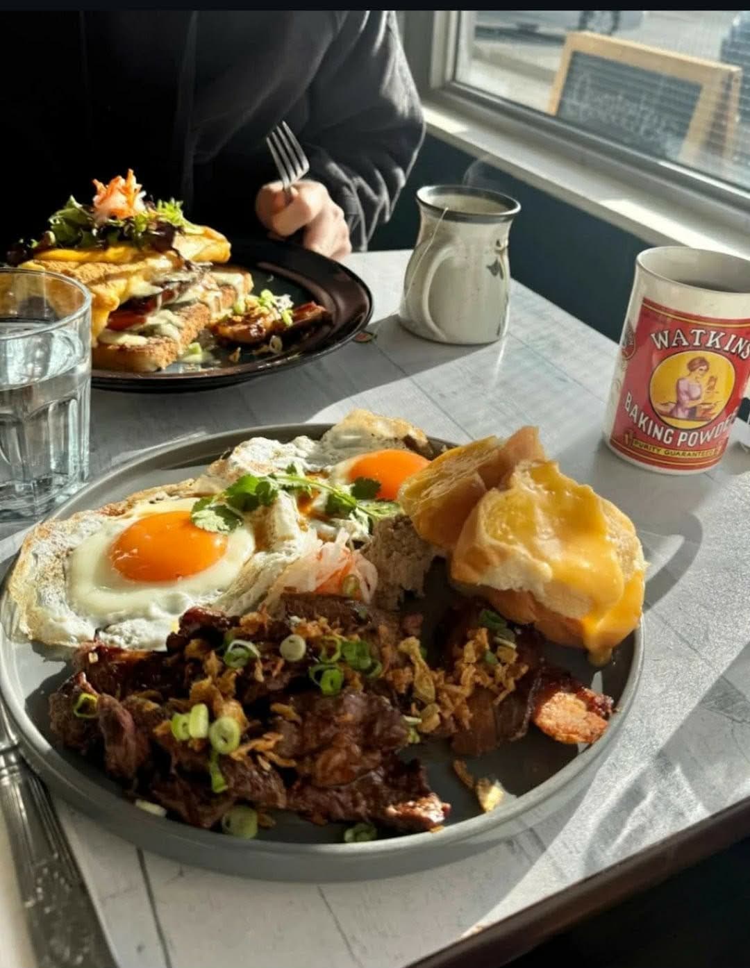 Vietnamese steak and eggs brunch on broken rice, served by the window at Bonjour Saigon in Calgary.