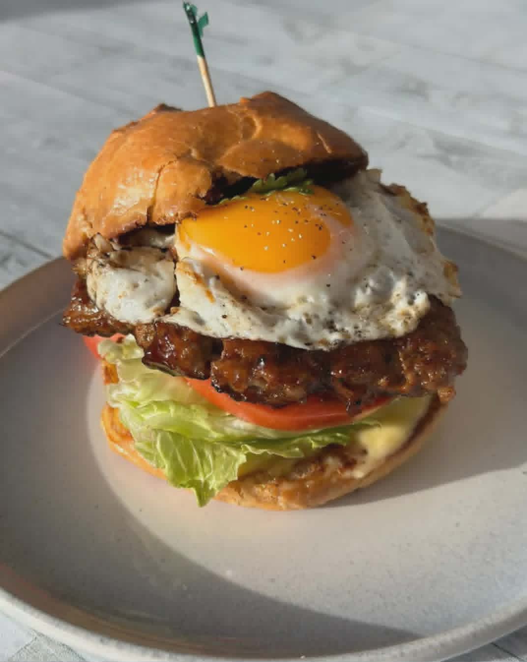 Viet-style breakfast smash burger with a fried egg, lettuce and tomato on a toasted bun.